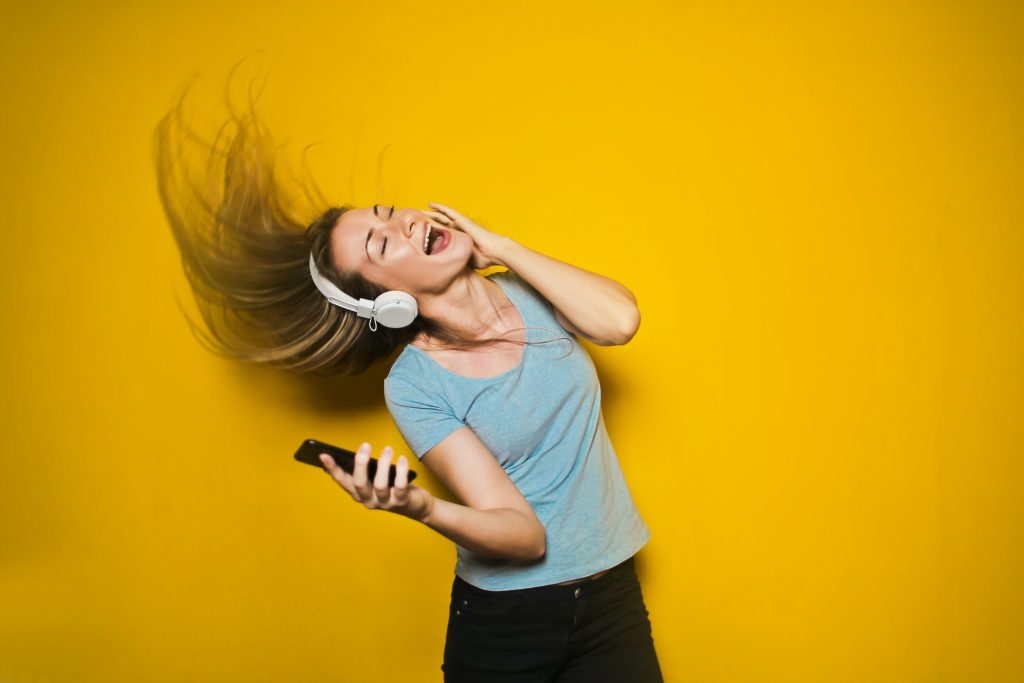 practicing mindfulness - girl happily listening to music with headphones